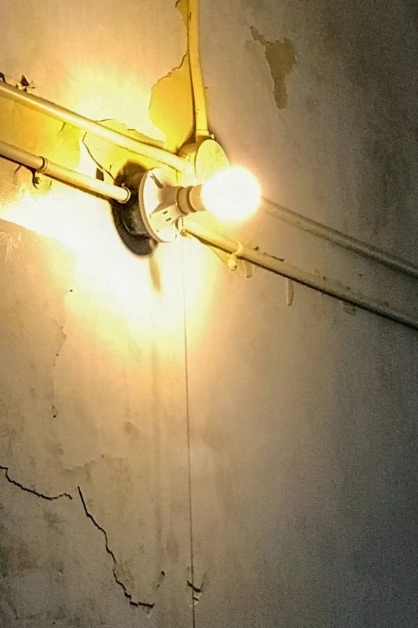 Stairwell with peeling paint, single bare bulb